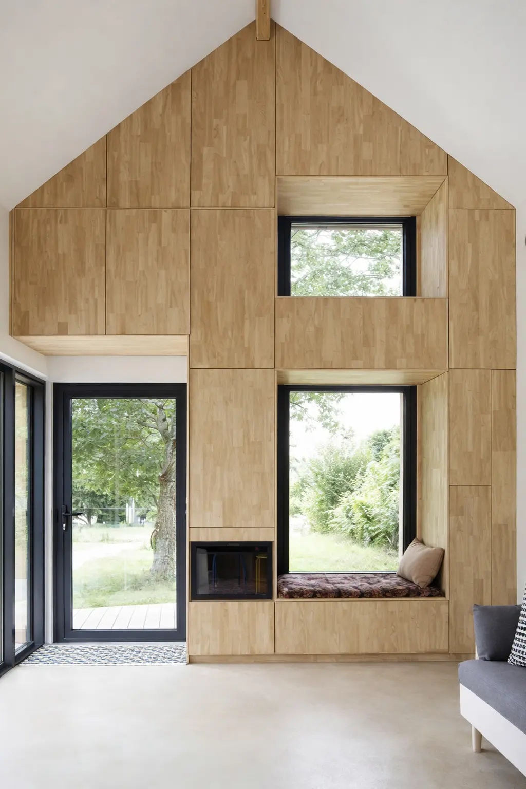 Tiny House plafond cathédrale grandes ouvertures baie fixe coin lecture banquette poêle et rangements intégrés menuiserie sur mesure